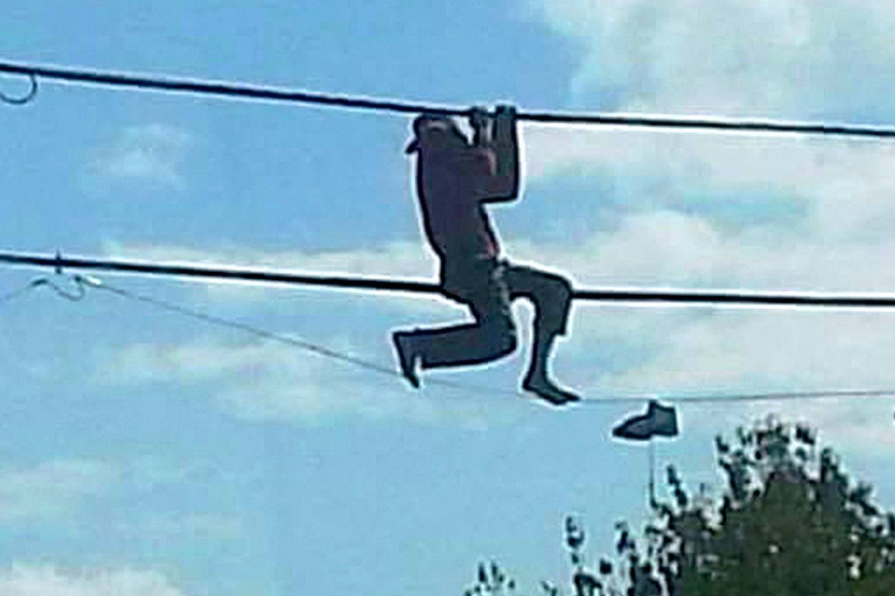 A shoeless man hangs from phone lines on North Oak Harbor Street Sunday. He told rescuers that he was trying to retrieve a pair of shoes. Photo by Robert Rizzo
