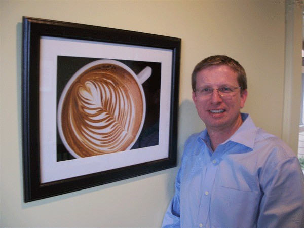 Dan Ollis relaxes next to a picture of the perfect cup of coffee taken on one of his trips to Guatemala.