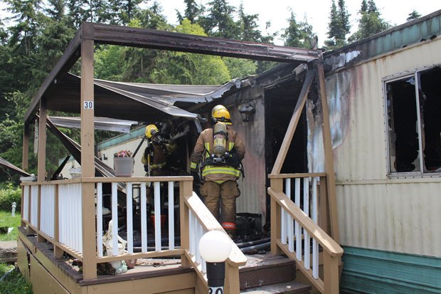 Firefighters check for hot spots after a fire destroyed a trailer home in Oak Harbor.