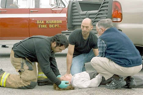 Ken Ellison kneels next to his wife Helen while she’s being checked before transport to Whidbey General Hospital.