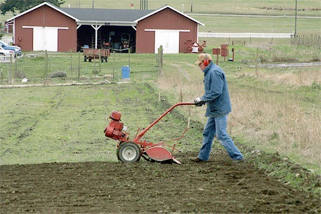 A student in the CSA training program at the Greenbank Farm tills the land. Efforts to place a conservation easement at the farm could add more protection to the farmland.