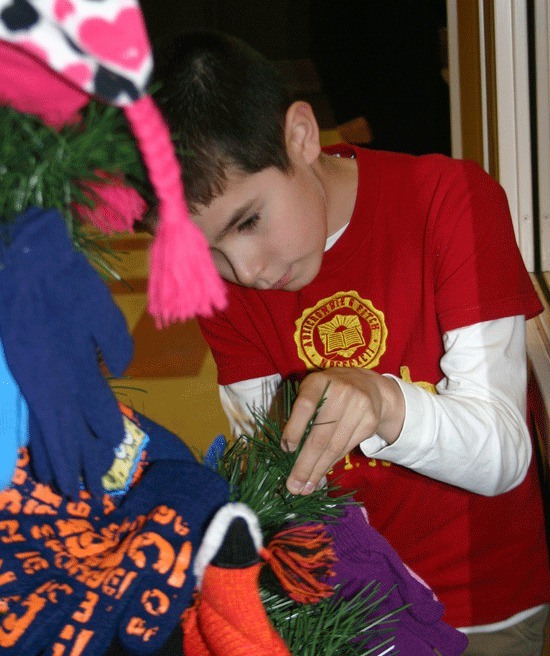 Broad View Elementary School student Alex Felger attaches a pair of gloves to the giving tree.