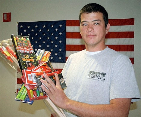 Oak Harbor firefighter Conor Ching holds some of the illegal fireworks the department confiscated last year.