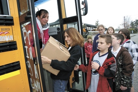 Help House board president Becky King grabs a box of canned goods from Christina Lafferty as the “Fill the Bus” campaign drives up to the food bank. She’s joined by students from the participating schools ­— North Whidbey Middle School and Olympic View