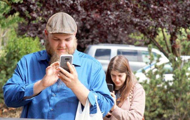Keath and Lisa Worley search for Pokemon creatures behind a convenience store in Coupeville Tuesday. The couple has enjoyed the new ‘Pokemon Go’ app on their phones. “We cleared them out here. On to the next location