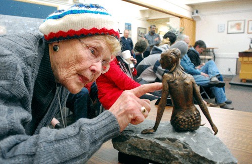 Helen Chatfield-Weeks examines a miniature bronze mermaid proposed for SE Pioneer Way during an Oak Harbor Arts Commission meeting Monday evening.