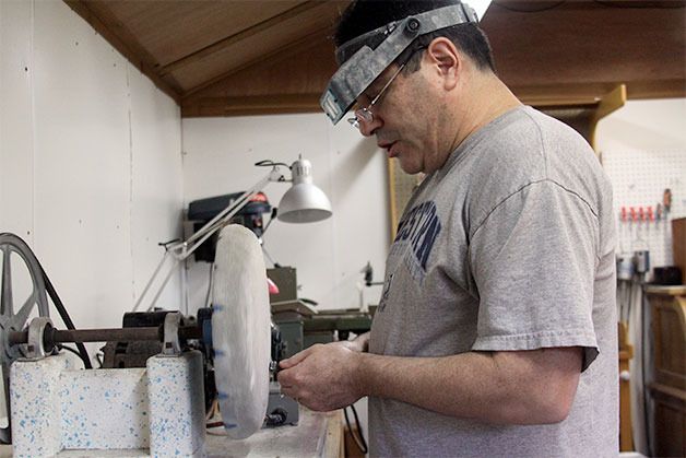 Paul Carter uses a buffer in his shop to smooth out a small stone and create a cabochon used in jewelry