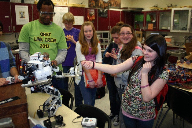 Eighth-grader Anya Fortune shakes hands with a robot while visiting Career-Technical classes at Oak Harbor High School Monday. Looking on are students Katie Schisler