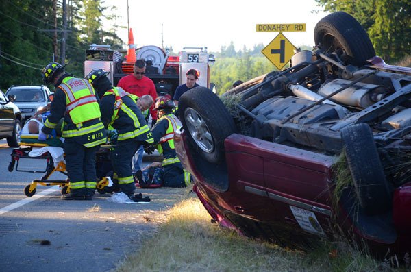 Central Whidbey Fire and Rescue firefighters assist Coupeville residents Victoria and Ricardo Reyes after their vehicle flipped over on State Highway 525 Saturday.