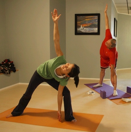 Laifong Ng and student Richard Fort reach into a yoga pose.