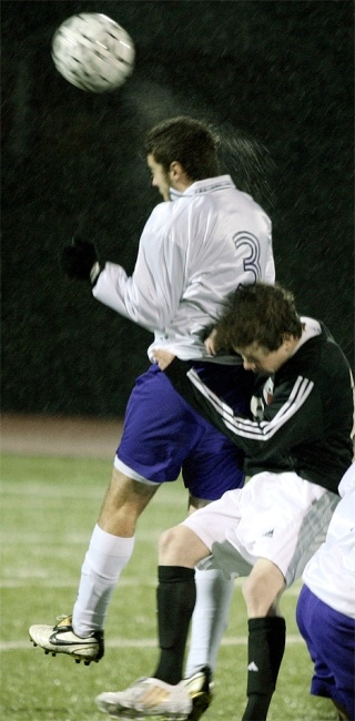 A spray of water flys from Oak Harbor midfielder Greg Wolfe’s head as he makes a pass in the driving rain during the WesCo North match.