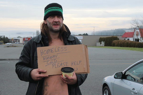 Jeff Pangburn stands at an entrance to the Safeway parking lot in Oak Harbor Wednesday seeking help from the public.