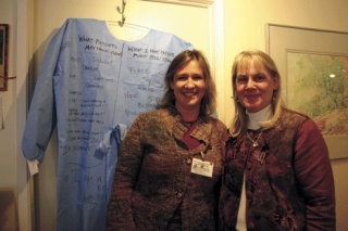 Event planners Carla Jolley and Renne Yanke pose in front of a chemo gown covered in signatures.