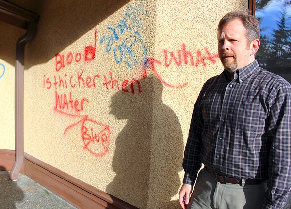 Rev. Jeffrey Spencer surveys some of the graffiti sprawled on Oak Harbor Lutheran Church.