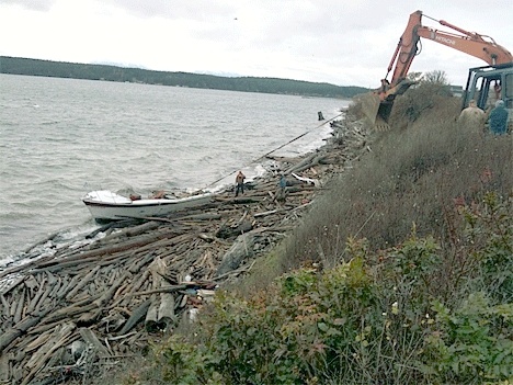 An excavator is used to pull a wrecked cabin cruiser from the shore of Penn Cove Saturday. The Washington State Department of  Natural Resources Derelict Vessels Program stepped in to remove the wreckage.