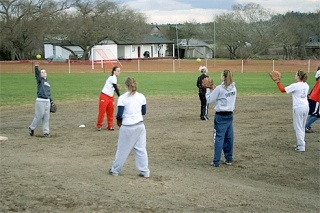 Members of the Coupeville High School softball team get their arms loosened up before the start of practice on a chilly day.