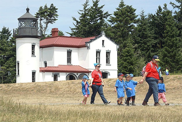 Visitors pass by Admiralty Head Lighthouse at Fort Casey State Park in Coupeville last month. The lighthouse is looking for volunteer docents to work in the museum and interpretive center.
