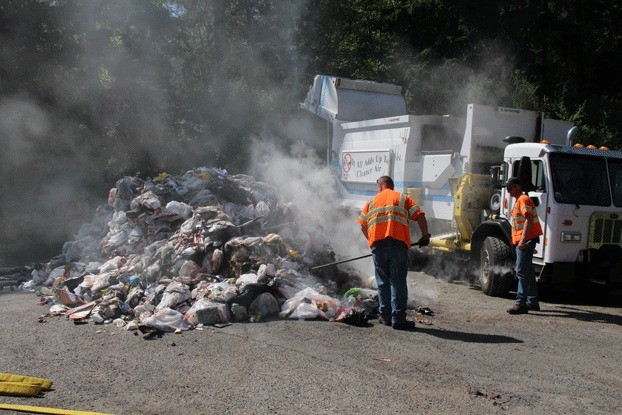 Solid waste collectors with Oak Harbor deal with a load of garbage that started on fire Wednesday.
