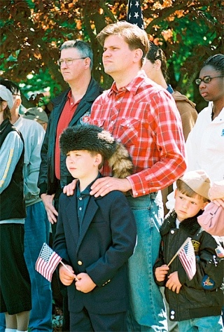 John Palm of Oak Harbor brought his boys to the Memorial Day ceremonies so they would learn to appreciate the meaning of the day. Listening with a coonskin cap on his head is Ambrose Palm