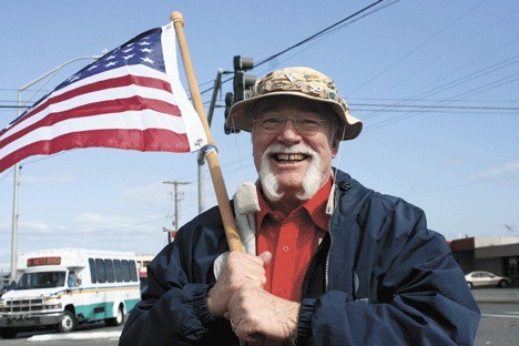 Bob Hagan waves the American flag along Pioneer Way Thursday for a Tea Party rally. Like several supporters