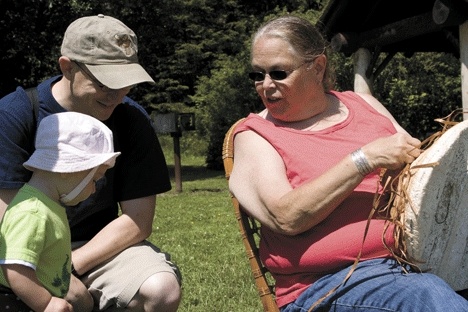 Jan Flagg of the Samish tribe demonstrates hat weaving to 1-year-old Aylee MacCabe and her dad Daniel