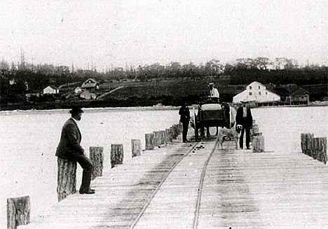 L.P. (Laurence Paul) Byrne sits to the left on his dock which led up to his storehouse on the beach