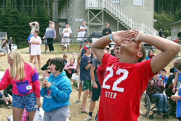 A counselor from Kiwanis Camp Casey catches a glimpse of parashooters with Oak Harbor’s Jet City Skydiving that dropped in to surprise attendees and deliver camp T-shirts at the camp for physically disabled children last week in Coupeville.