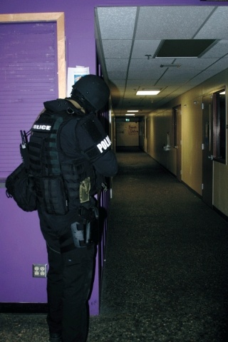 An armored officer secures the hallway at Oak Harbor High School during a mass casualty drill Monday night. The hostage taker