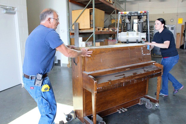 City employee Tom Wade and Sunshine Fenton of Mather Auctioneers move one of three pianos up for auction Saturday.