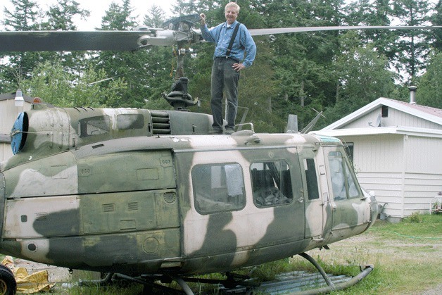 Brien Lillquist stands atop his Vietnam-era helicopter that has been on his Swantown Avenue property for the past five years. He sold his landmark  helicopter and it was removed from his yard Tuesday.