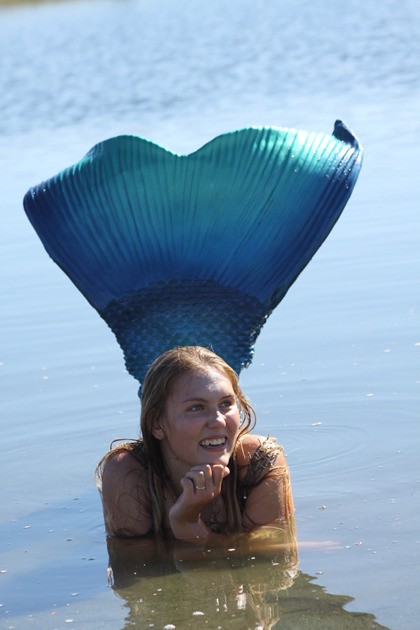 Hannah Gluth receives rocks and other gifts from fascinated and adoring children near the lagoon at Windjammer Park Wednesday. Her mermaid outfit was a hit among kids and moms alike.