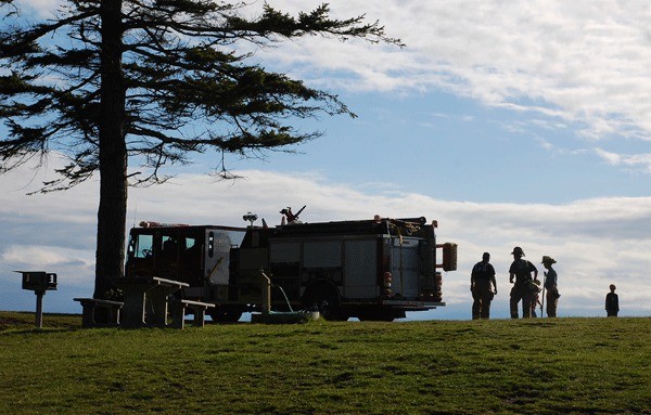 North Whidbey Fire and Rescue firefighters pause while fighting a grass fire at Fort Ebey State Park this past August. The fire district is negotiating with the Washington State Parks and Recreation Commission to begin charging for calls other than fires at Deception Pass State Park.