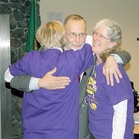 Rick Schulte hugs Lynn Goebel and Kathy Chalfant after a speech Monday