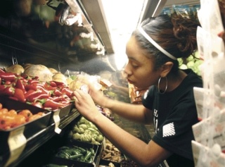 Oak Harbor High School senior Tiersha Cutler stocks produce at Safeway Wednesday morning. She was one of 40 DECA students who descended on the local supermarket to gain real world work experience.