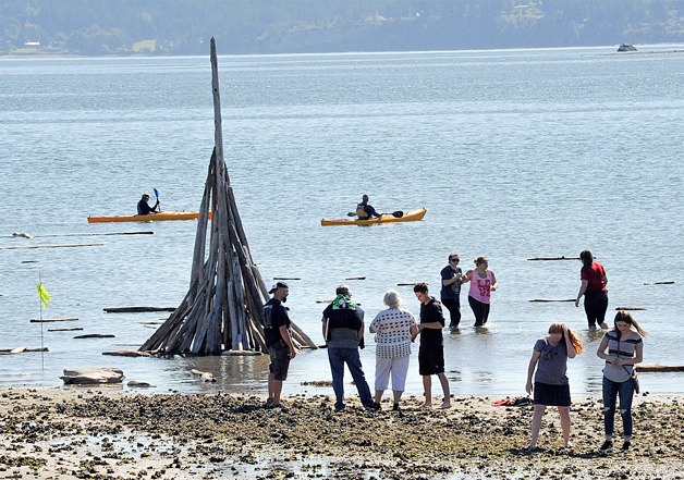 Driftwood sculptures are reclaimed by the incoming tide during Driftwood Day last year. The event is set for noon Saturday.