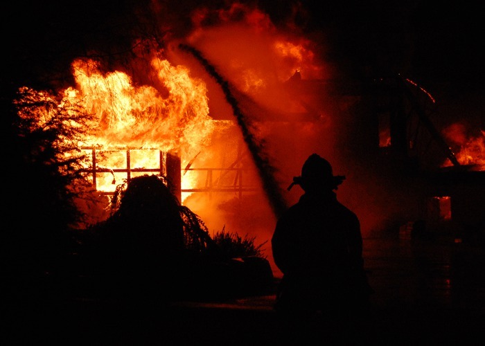 A Central Whidbey Fire and Rescue firefighter douses the flames of a burning Coupeville home in 2011. The district is running a levy lid lift this month in hopes of addressing a decline in volunteer levels.