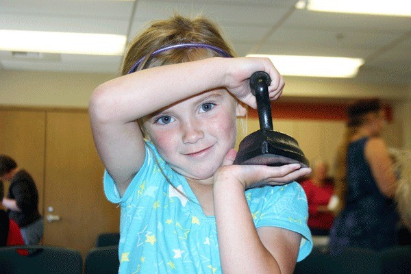 Five-year-old Cayla Turner discovers how heavy irons used to be in the 1800s. Cayla