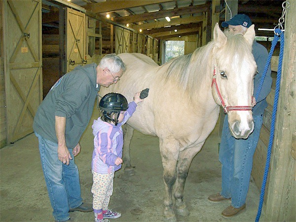 Rider Kaitlynn Eaton tends to a horse named Dusty with the help of HOPE volunteers Larry Eaton