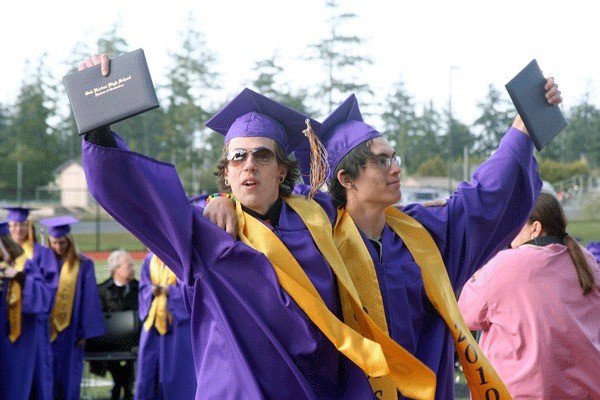 Oak Harbor High School graduates Sean Johnson and John Freitas show their diplomas during Monday’s ceremony at Wildcat Memorial Stadium.