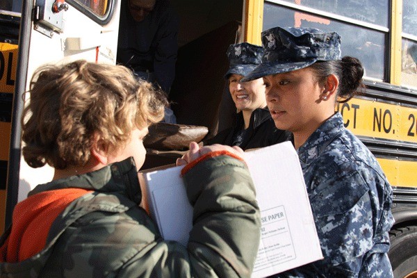 Petty Officer 1st Class Roxanne Martinez of VQ-1 hands off a box of food to a young assistant as part of the “Fill the Bus” donation drive held by the Oak Harbor School District. More than 17