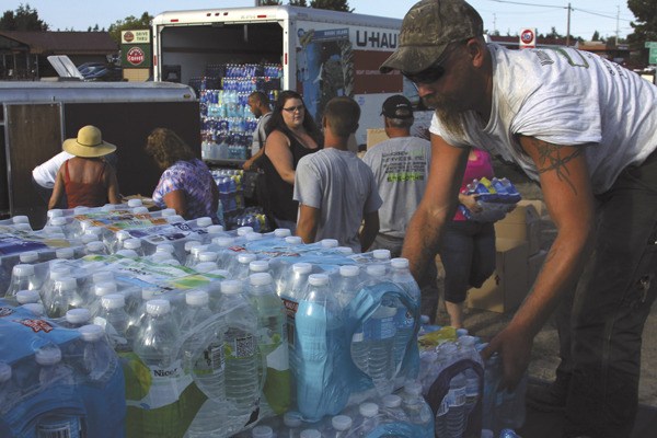 Ty Wahl loads a pickup with cases of water destined for wildland firefighters and displaced fire victims in Ferry County. A group from Oak Harbor and Coupeville set up a collection center in Oak Harbor to answer a plea for help from Ric Sanders