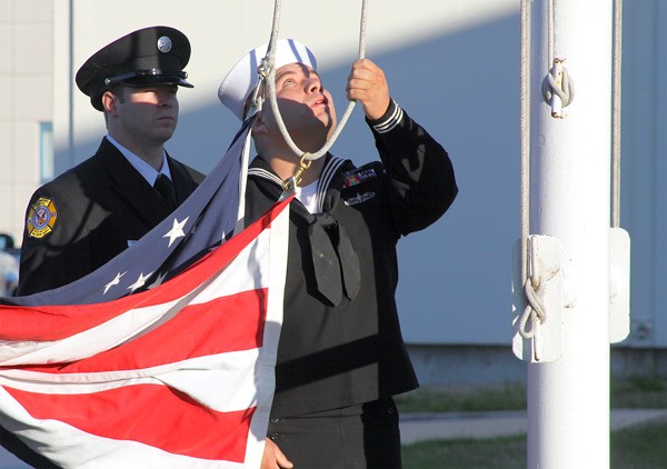 A sailor raises the flag half-mast during a 9/11 ceremony at Whidbey Island Naval Air Station Friday.