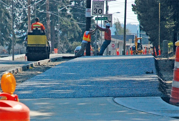 GG Excavation workers position a road sign near the intersection of North Oak Harbor Road and Crosby Avenue. Island-medians there and at the intersection at Seventh Avenue had to be removed