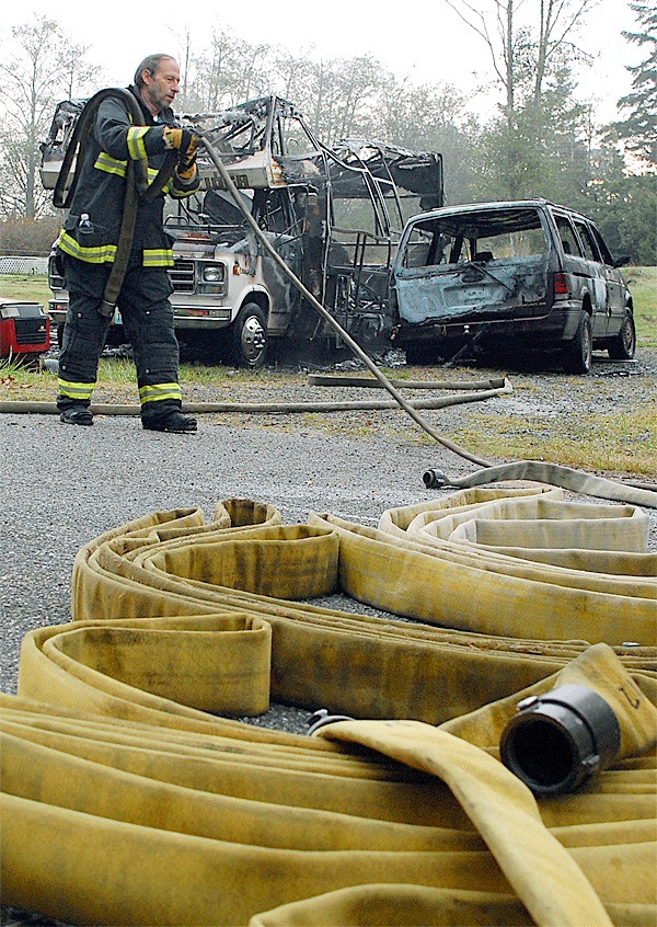 A Central Whidbey Fire and Rescue firefighter wraps up after a motor home fire in Greenbank Wednesday morning.