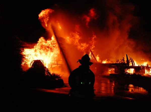 Central Whidbey Fire and Rescue firefighter Dustin Gardner mans a hose at a house fire on NE Leisure Street in Coupeville early Tuesday morning.