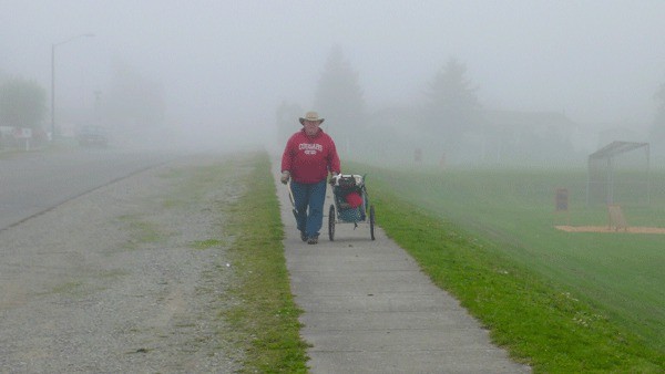 Oak Harbor resident David Lura walks through the fog near the high school Thursday while picking up litter along the road. Fog is expected to persist through the weekend.