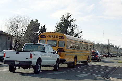 A white Ford F-250 pushes a 1989 Oak Harbor School District Blue Bird bus out of the way of traffic Friday afternoon until a tow truck could pull it back to the bus barn.