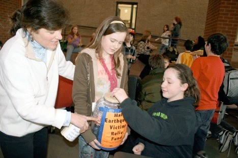 Coupeville Middle School science teacher Terry Welch watches as sixth-grader Julia Jones contributes some coins to benefit the victims of the earthquake in Haiti. Students in the Coupeville School District have held several coin drives in recent days.