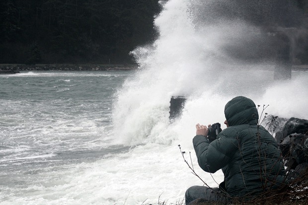 A storm watcher gets an upclose look at the waves that crash into a seawall near the Coupeville ferry landing Thursday.