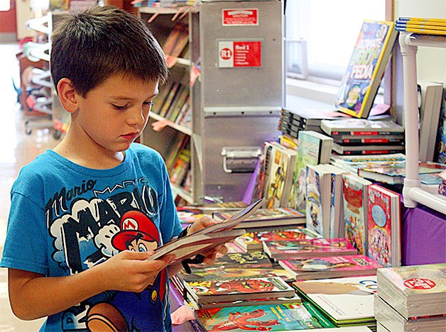 Second-grader Grayson Darrow looks through the selection of books at Crescent Harbor Elementary’s book fair Wednesday.